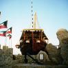 Al Boom, Kuwait, september 1995. Rolleiflex 3.5 B, Kodak Gold 100. Mohammedi II sits at the Kuwait SAS hotel and contains the Al Boom restaurant. Despite its size, it's rather cramped inside. The traditional arab dhow (or boom, as it's known in Kuwait) is still common in this part of the world. They're still being built today, and the design hasn't changed significantly over centuries. Neither have the building materials: teak and iron nails, handcrafted of course. Mohammedi II has now been supplemented by an enormous sister ship, Al Hashemi II, officially the world's largest dhow, which contains conference and banquet facilities (the latter typically taking on epic proportions as is the custom in the gulf). Both vessels sit on land and never actually sailed! Scat trivia: those two tubs dangling from either side of the stern were the ship's crapper!